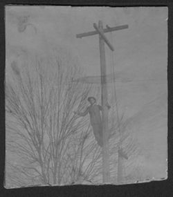 Howard Carmichael standing on telephone pole, Montana ca. 1910.
