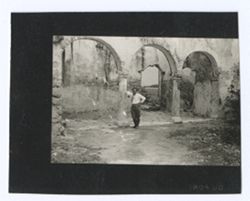 Item 1187. Eisenstein in courtyard, standing in middle of triple-arched entry way.