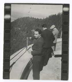 Item 1190. Three men standing by concrete railing, with mountains in background. See Item 533 above for similar setting.