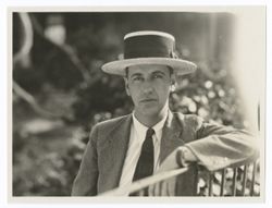 Item 0577. Unidentified man in business suit and high-crowned straw hat, with left arm on a railing.