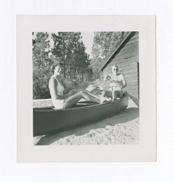 Elderly man and young woman sitting in a canoe on a beach