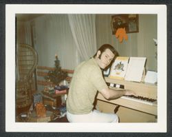 Randy Carmichael playing piano, with Christmas decorations in the background.