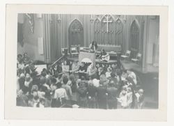 People linking arms with girl playing guitar in the church