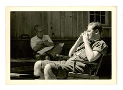 Two men sitting in front of a cabin