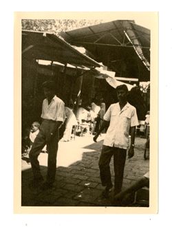 Men walk past market stalls