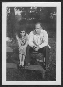 Georgia Carmichael and an unidentified man seated on a picnic table.