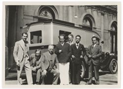Item 0466. Two similar shots of seven men in front of a van parked in front of a large government (?) building. Tissé, second from left - Eisenstein, center - Alexandrov, third from right. Others unidentified. Tissé and man to his left seated on rear bumper of van.