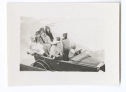 Item 0613. Shots of parade of automobiles around arena. Medium shot of auto with 6 young women seated in rear.
