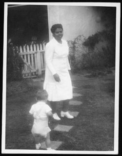 Eva Chatman with Hoagy Carmichael's son, Randy, standing in walkway of a house, 1944.