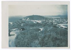 Item 69. Color shot of town on seacoast (?). Trees and curving roads in foreground.