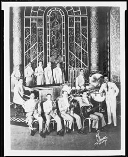 Twelve unidentified musicians with decorative stained glass in the background.