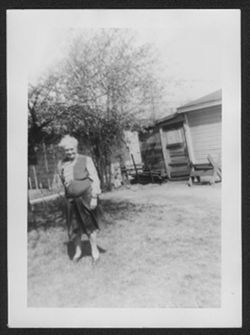 Clara Hall at 80 years old standing in a yard.