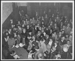 Hoagy Carmichael at a table, autographing a book, surrounded by many people.