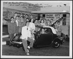 Musicians posing around a car in the parking lot of the Radio City Music Hall, New York City.