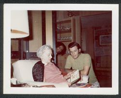 Georgia (Carmichael) Maxwell and Randy Carmichael looking at Christmas cards with an unidentified woman in the background.