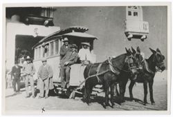 Item 0391. Group of people gathered around mule-drawn trolley bus on railroad track.