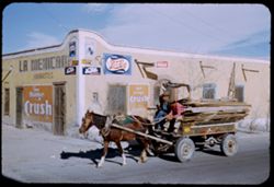 A Mexican wagon passes a corner store.
