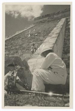 Item 0360. Tissé, seated on ground behind camera at far left, and Eisenstein, seated on trunk, at base of Castillo stairs. Unidentified man seated on steps.