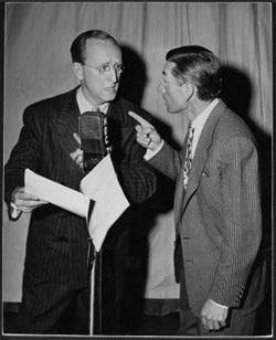 Hoagy Carmichael with Kay Kyser in front of a microphone in an NBC studio during the radio show Something New.