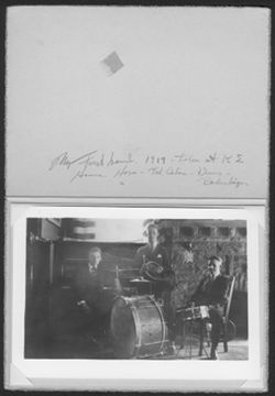 Matted photo of Hoagy Carmichael sitting at a piano beside Ted Cadou, horn, and Beshenbeizer, drums, in the Kappa Sigma fraternity house.