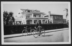 Man identified as George posing on a bicycle in front of a house.