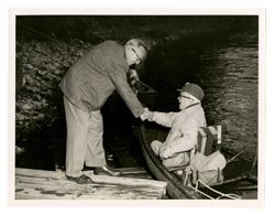 Roy Howard greeting another man from a canoe