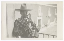 Item 29. Julio Saldivar on balcony overlooking courtyard, playing a small saxophone.