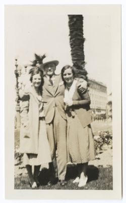 Item 0549. Hunter Kimbrough in city park or plaza with two unidentified women. Both pictures slightly out of focus. Standing between the women, his arms around their shoulders.