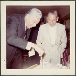 Caesar Romero and Hoagy Carmichael standing over a cake.