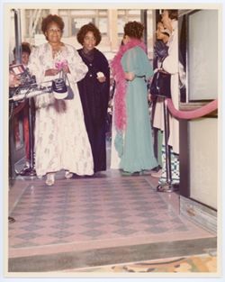 Picture of three unidentified women, possibly Katherine Dunham, Barbara Felton, and Margot Hicks, walking past crowd