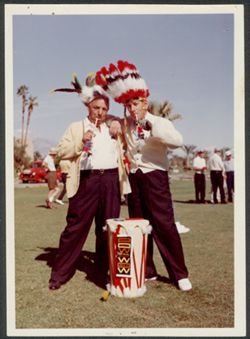 Hoagy Carmichael and an unidentified man in mock Native American headdress at a golf course.