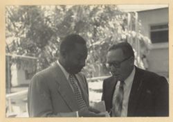 Two men in business suits talk together