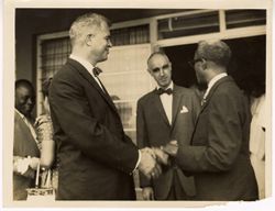 Ambassador C. T. O. King greets men outside building