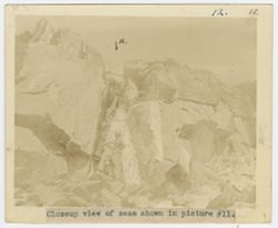 Man stands next to a seam in the rock face