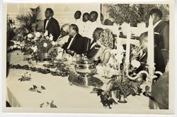 President William V. S. Tubman sits with guest listening to speaker at a reception