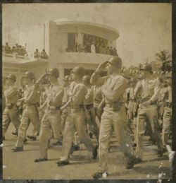 Military men march in parade and salute outside Executive Pavilion