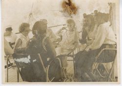 Women sit at a table on a deck and chat