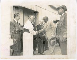 President William V. S. Tubman shakes hands with a spiritual leader, officials standing by