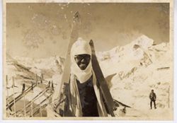 Coocoo poses with skiis in front of snow covered peaks