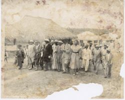 Officials walk with locals along street of village