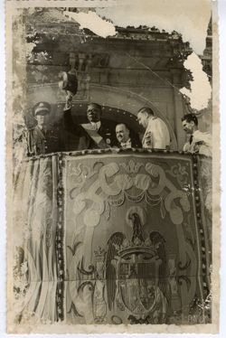 Presiedent William V. S. Tubman waves top hat on balcony with military officials