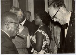 President William V. S. Tubman smokes cigar and talks with Swedish Prime Minister with small gathering in background
