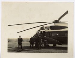 Men gather around helicopter with U.S. flag on it