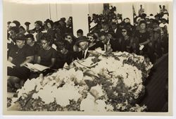 Flower covered casket and guests during funeral service