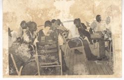 Men sitting around tables on the deck of a boat