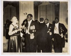 President William V. S. Tubman takes a moment to acknowledge the camera while Paul Magloire and other reception guests mingle