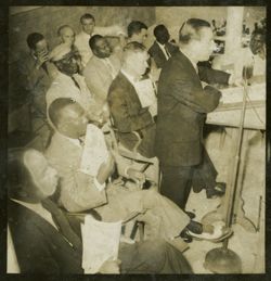 Dignitary speaks from behind a lectern, President Tubman is seated beside him