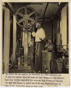 Man touches fly wheel of drop hammer