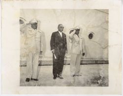President William V. S. Tubman stands with two military officials saluting in front of a ship