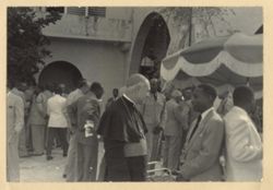 Man speaks to priest while guests mingle in background